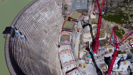 aerial drone top down shot over dam under construction in grimsel pass, swiss mountain, switzerland on a sunny day