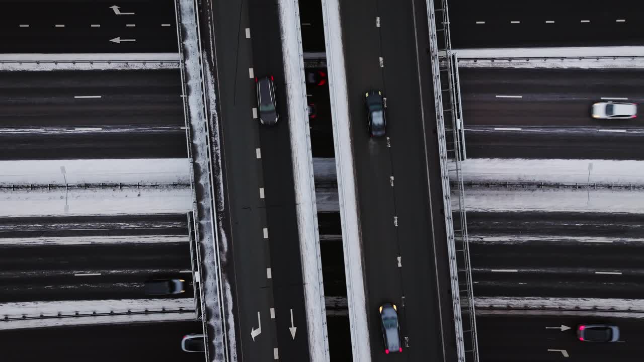 Snowy static aerial of dark asphalt roads in winter, moving traffic at sunrise