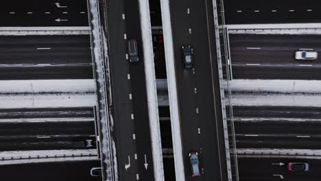 snowy static aerial of dark asphalt roads in winter, moving traffic at sunrise