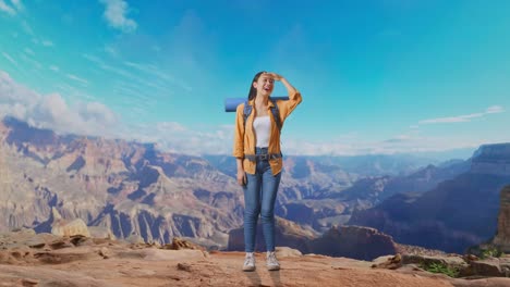 full body of asian female hiker with mountaineering backpack hand forehead smiling and looking distance while traveling at the top of mountain