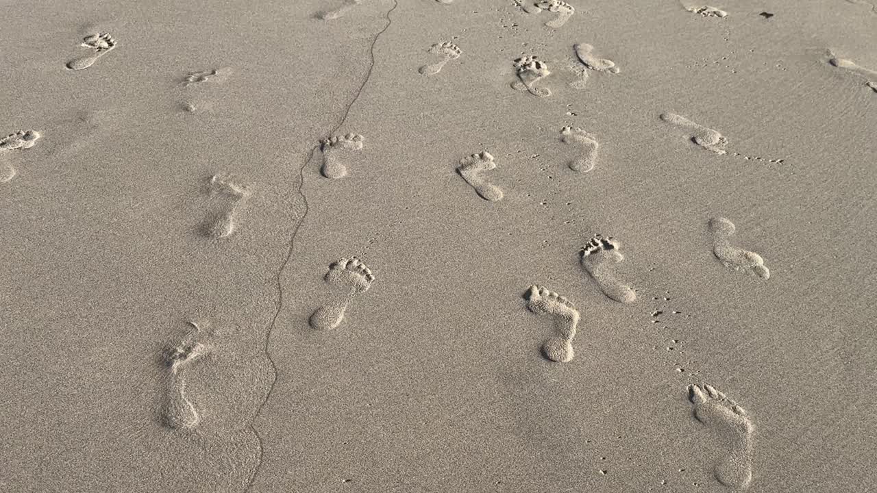 Pegadas na areia da orla em uma praia na Cidade do Cabo, África do Sul