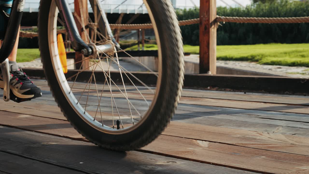 A person riding a bicycle across a wooden bridge in a park