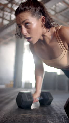 vertical video: lifting dumbbell, woman in gym focusing on intense workout session