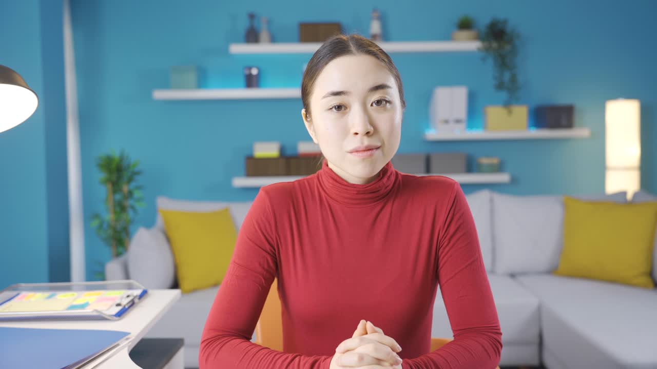 아시아 여성은 노트북에서 보는 것에 불만을 품고 카메라를 향해 머리를 흔들고 있습니다.