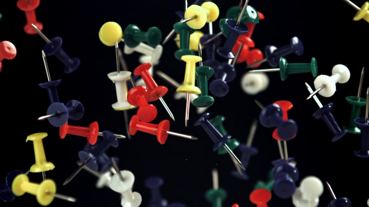 Vibrant Pushpins Falling and Floating in Slow Motion on Black