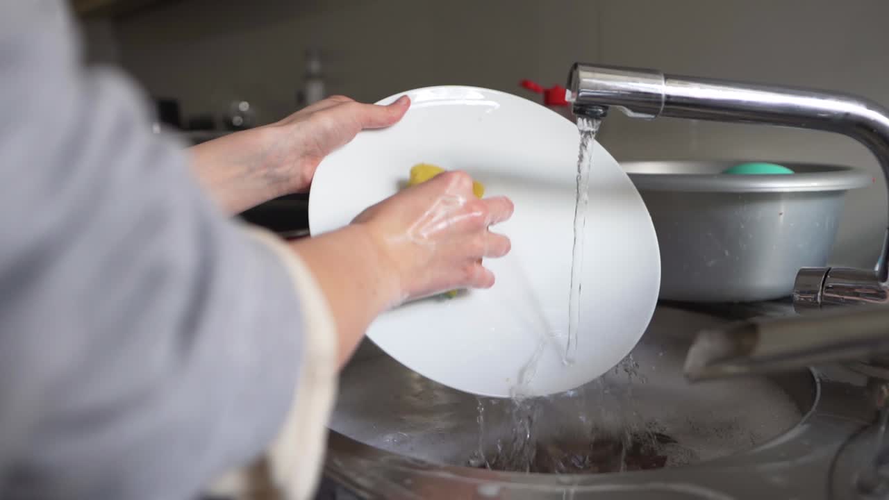 Mujer lavando platos en el fregadero de la cocina