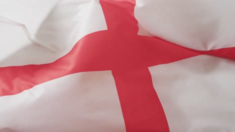 White-rugby-ball-rolling-over-waving-flag-of-england-with-copy-space,-in-slow-motion