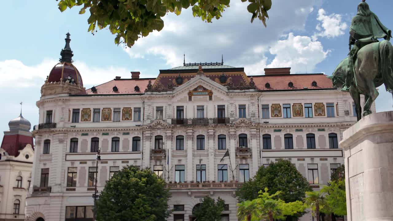 Exterior view of Baranya County Hall in Pécs with the Hunyadi Statue in the foreground, highlighting historic architecture and landmark significance