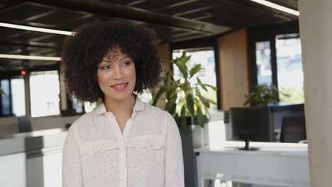 smiling businesswoman standing in modern office with plants and computers