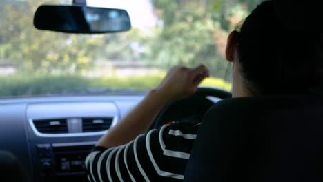 young woman driving in a car, dancing and having fun in country street on sunny day.