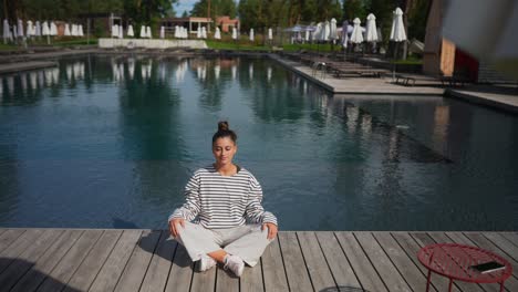 woman meditating by the pool