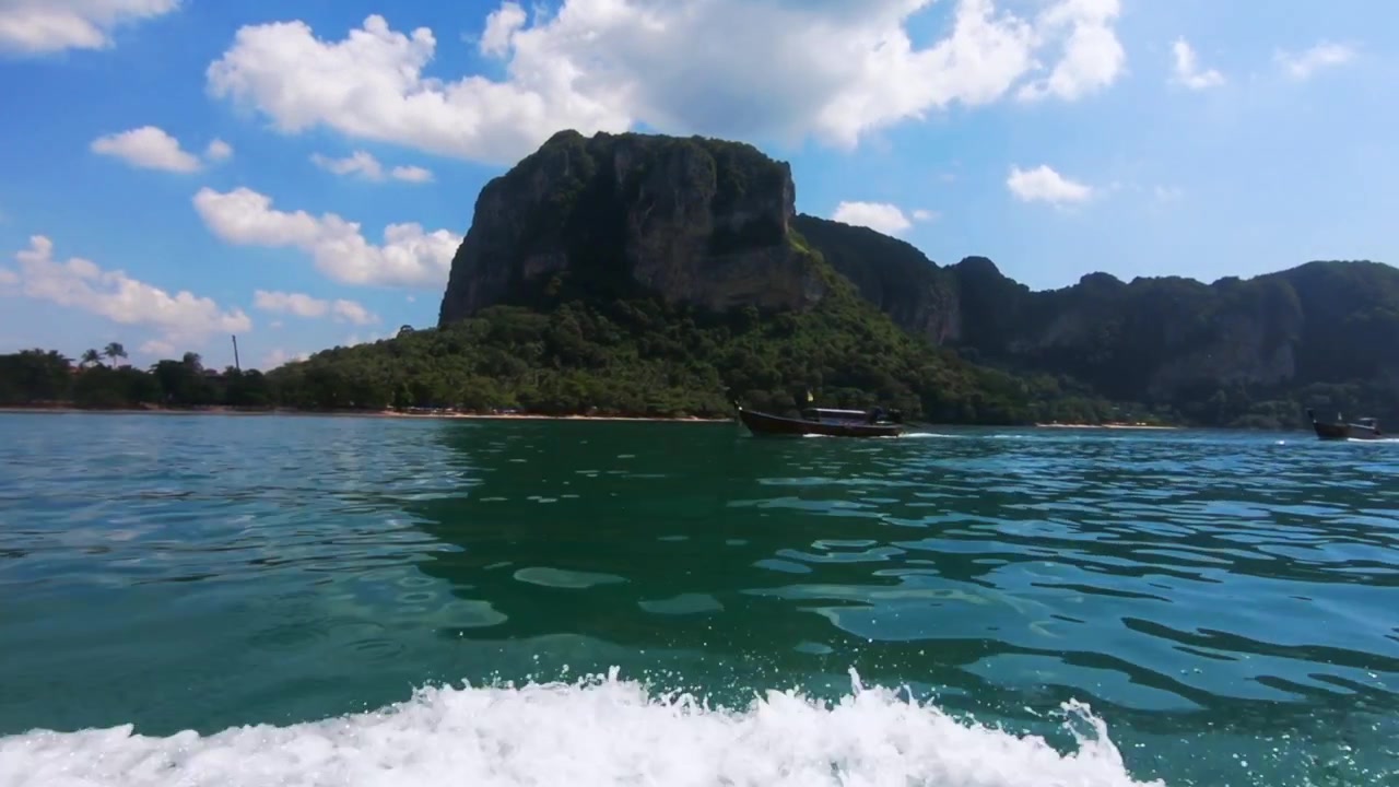 Scogliere di Railay con il mare in primo piano, filmate in Thailandia, Asia, a 120fps cinematografici e stabili, con una barca che procede in direzione opposta.