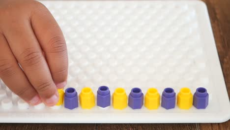 niño jugando con clavijas coloridas en una tabla de clavijas