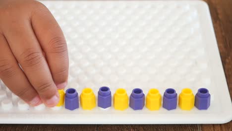 child playing with colorful pegs on a peg board