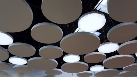 round decorative elements of diverse size hanging on the ceiling of the room. lamps of the same design among the pieces. low angle view