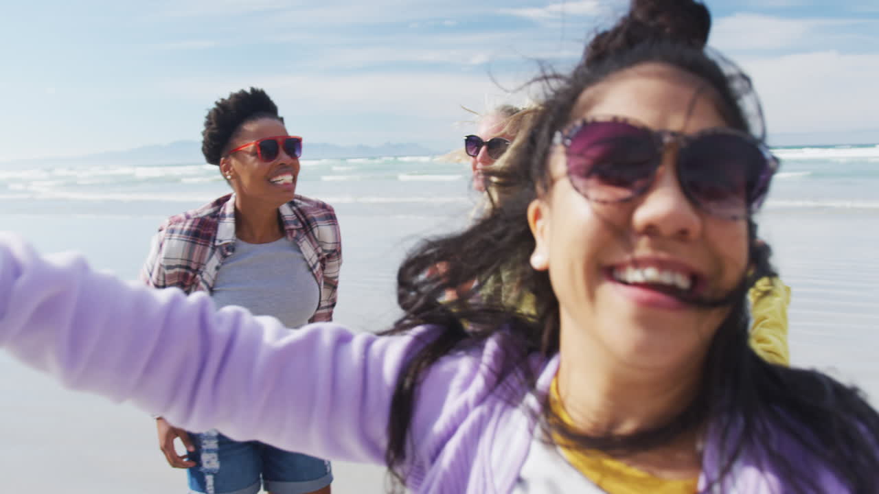un grupo feliz de amigas diversas divirtiéndose, bailando y sonriendo en la playa