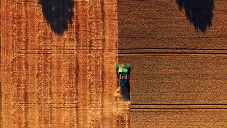 Top-View-Of-Combine-Harvester-Machinery-Working-In-Field-During-Sunset