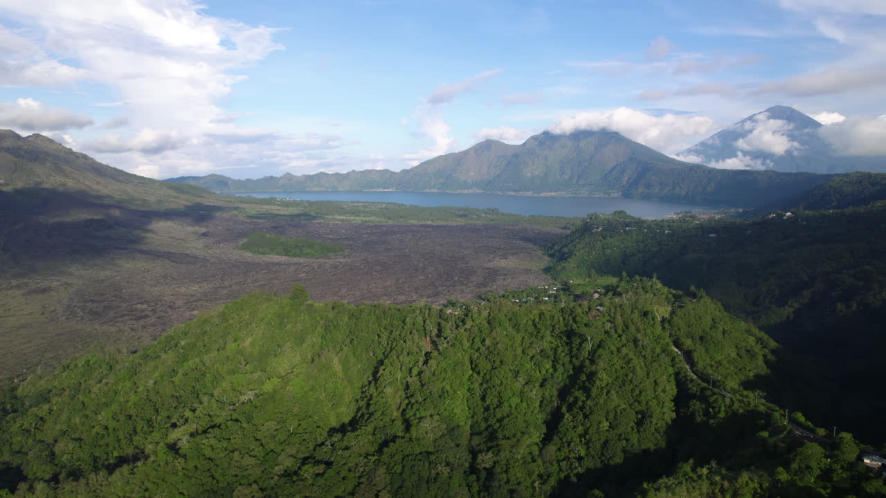 Aerial view rising over highlands toward lake Batur, sunny day in Bali Indonesia