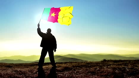 exitoso hombre silueta ganador agitando bandera de camerún en la parte superior del pico de la montaña. fondo de bucle cinemagraph