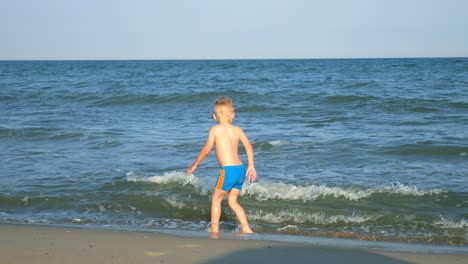 a little boy runs away from the waves on the beach sea.