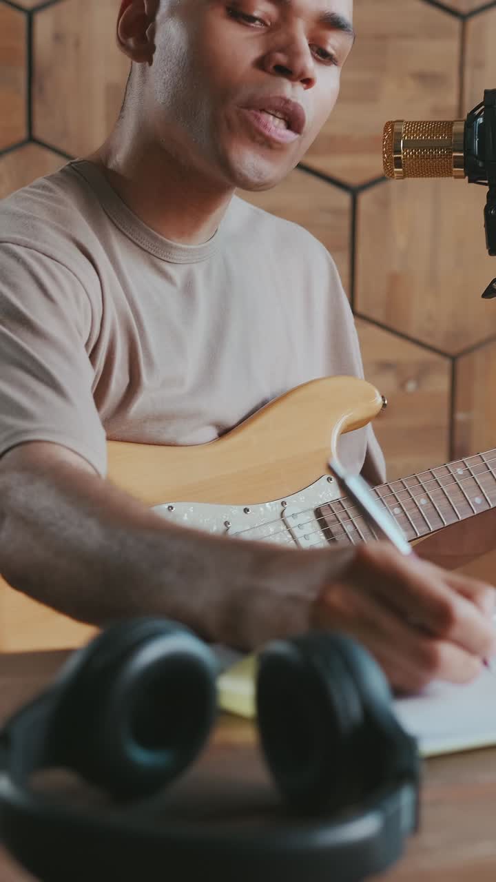 African american man guitarist comes up with music and making notes on notepad