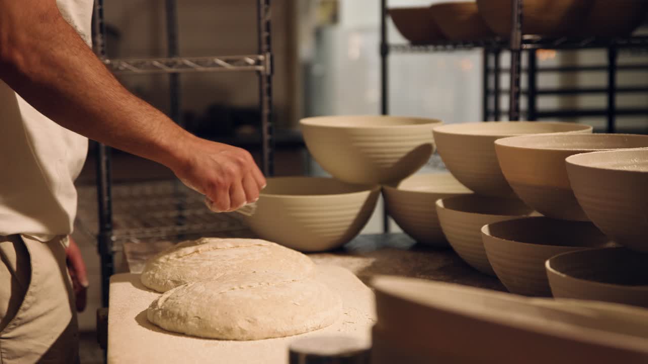 Panettiere che infarina e incide l'impasto di pane fresco in una panetteria