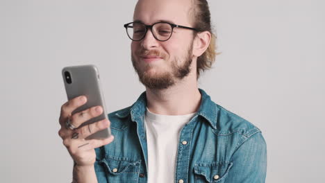 joven caucásico usando el teléfono inteligente en la cámara.