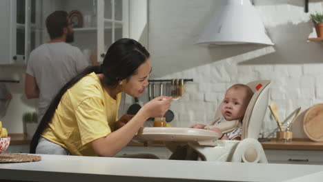 family feeding a baby in the kitchen