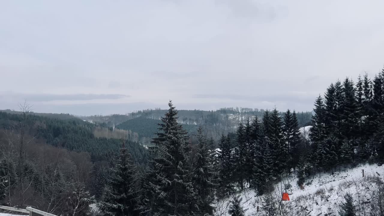paisaje invernal con colinas y bosques cubiertos de nieve y cielo nublado