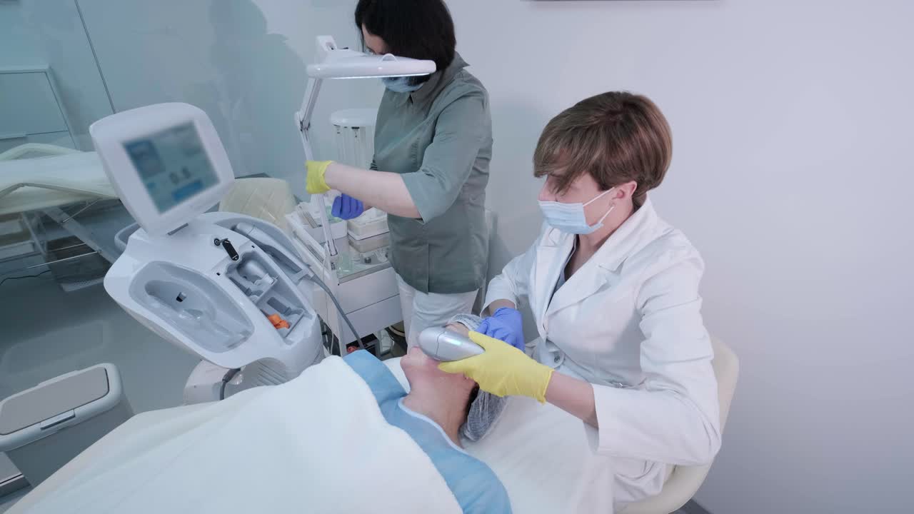 rejuvenecimiento profesional de la piel del rostro, procedimiento de lifting. el cosmetólogo utiliza un dispositivo de ultrasonido moderno. cosmetología de hardware