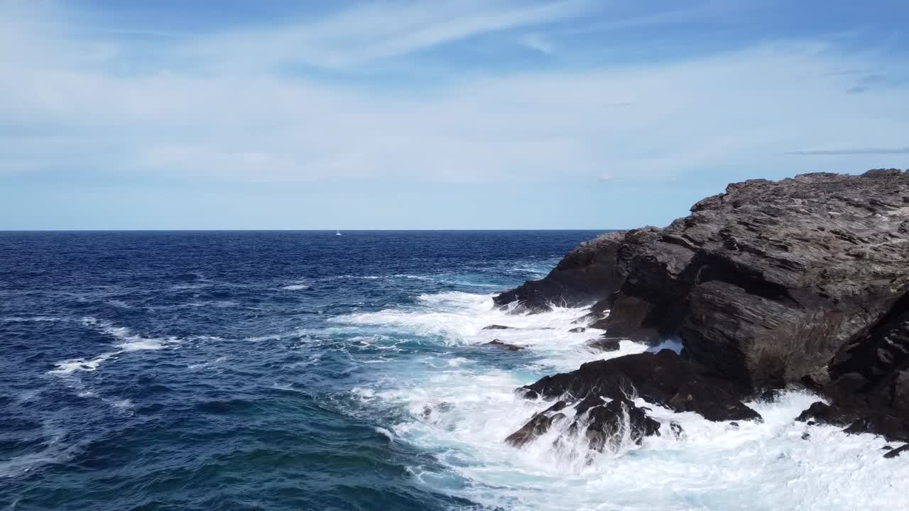 deslumbrante mar da sardenha com rochas escuras e um veleiro no horizonte