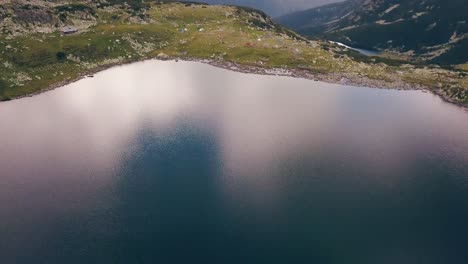 wide aerial drone slowly flying over a lake looking down onto a valley a mountain range