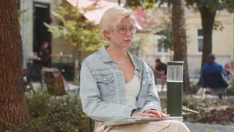 european young woman freelancer in city street closes laptop screen finishing working online job