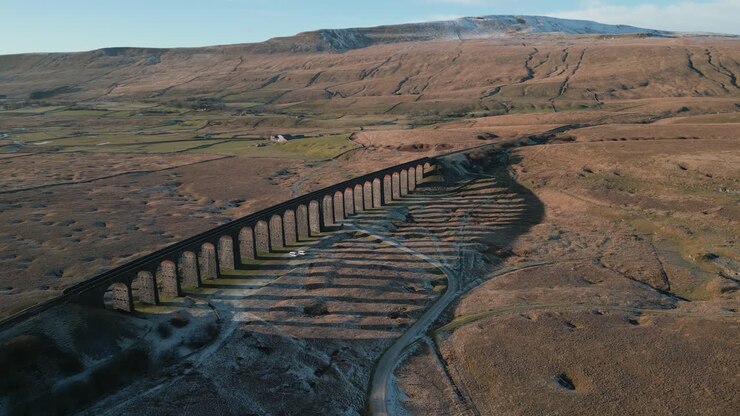 Railway bridge high altitude approach with long shadows in winter at Ribblehead Viaduct UK
