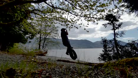 swinging on rope with lake and mountains in the background