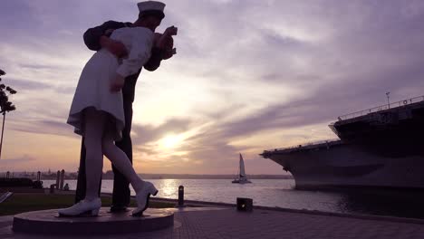 a famous statue of a sailor kissing a girl at the end of world war two at sunset in a san diego park