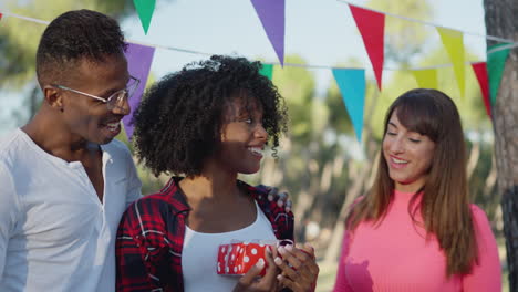 friends celebrate birthday in a park with gift giving and joy
