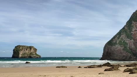 beach view of castro ballota islet from ballota beach in asturias, showcasing the coastline and clear skies