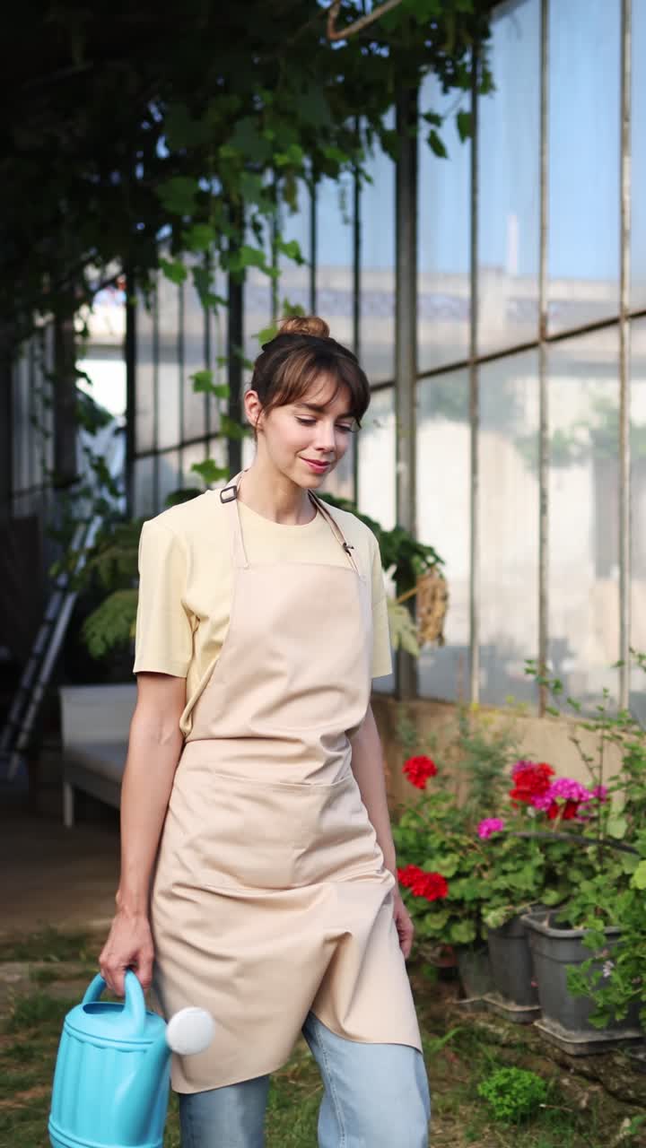 Giardiniera che cammina con annaffiatoio in serra
