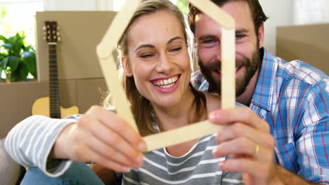 cute couple smiling behind a wood shape