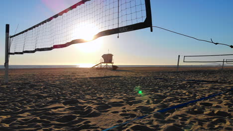 vuelo bajo a redes de voleibol vacías con hermosa puesta de sol y torre de salvavidas en la distancia, drone aéreo 4k en huntington beach, ca