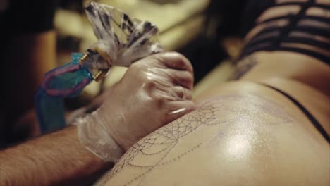 artista del tatuaje aplicando tatuaje en la espalda de la mujer