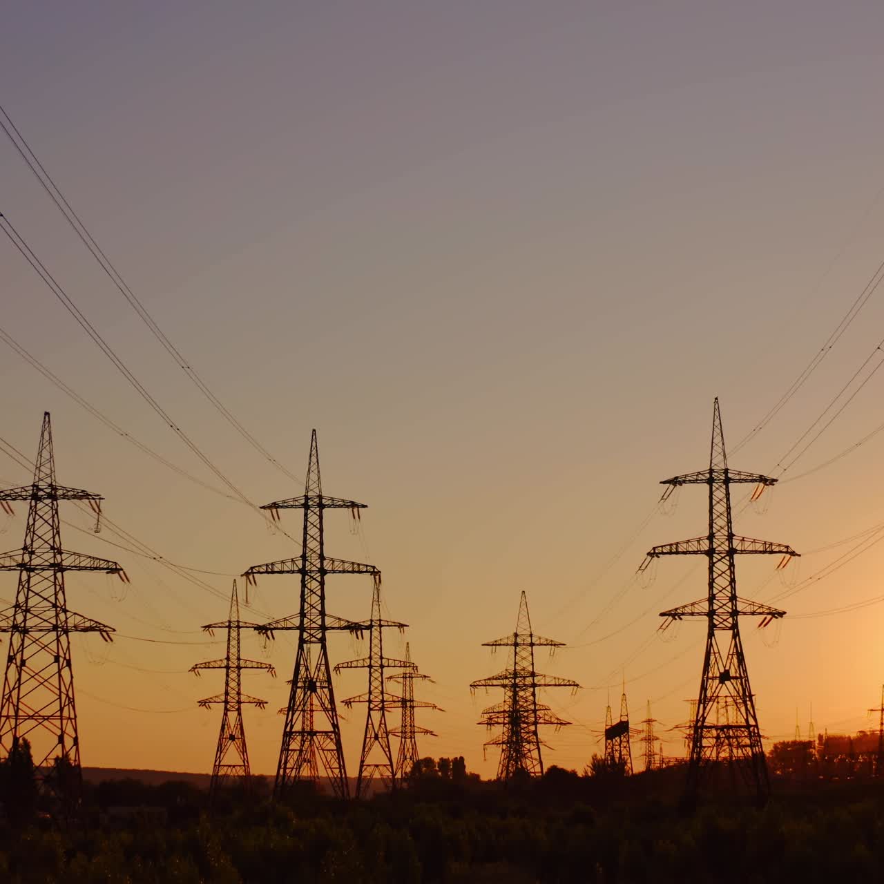 High-voltage electric line at sunset. Silhouettes of electric pylons on the setting sun background. Electricity distribution station.