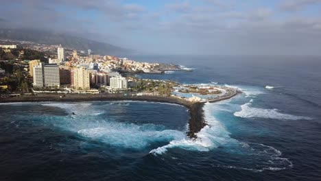 panorama aéreo de puerto de la cruz resorts y piscinas rodeados de olas marinas, tenerife, islas canarias, españa.