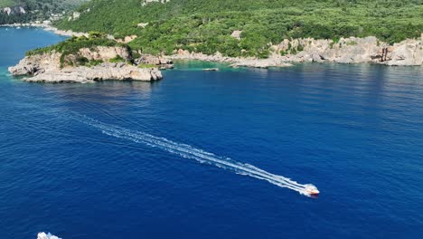 Un-Barco-Navegando-Cerca-De-Las-Costas-Rocosas-De-La-Isla-De-Corfú,-Grecia,-En-El-Mar-Jónico,-Día-Soleado,-Vista-Aérea