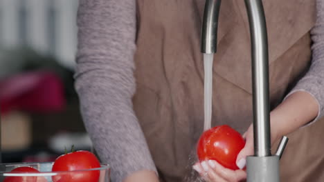 A-woman-washes-tomatoes-under-a-stream-of-water-from-a-tap-1