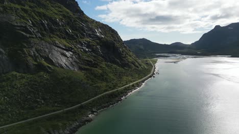 Vista-Aérea-Que-Muestra-Un-Fiordo-En-Lofoten,-Noruega,-A-Lo-Largo-Del-Cual-Discurre-Una-Carretera-Con-Montañas-En-Todas-Las-Direcciones