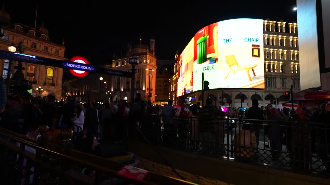 Bustling night scene at Piccadilly Circus in London with neon lights and busy crowds around