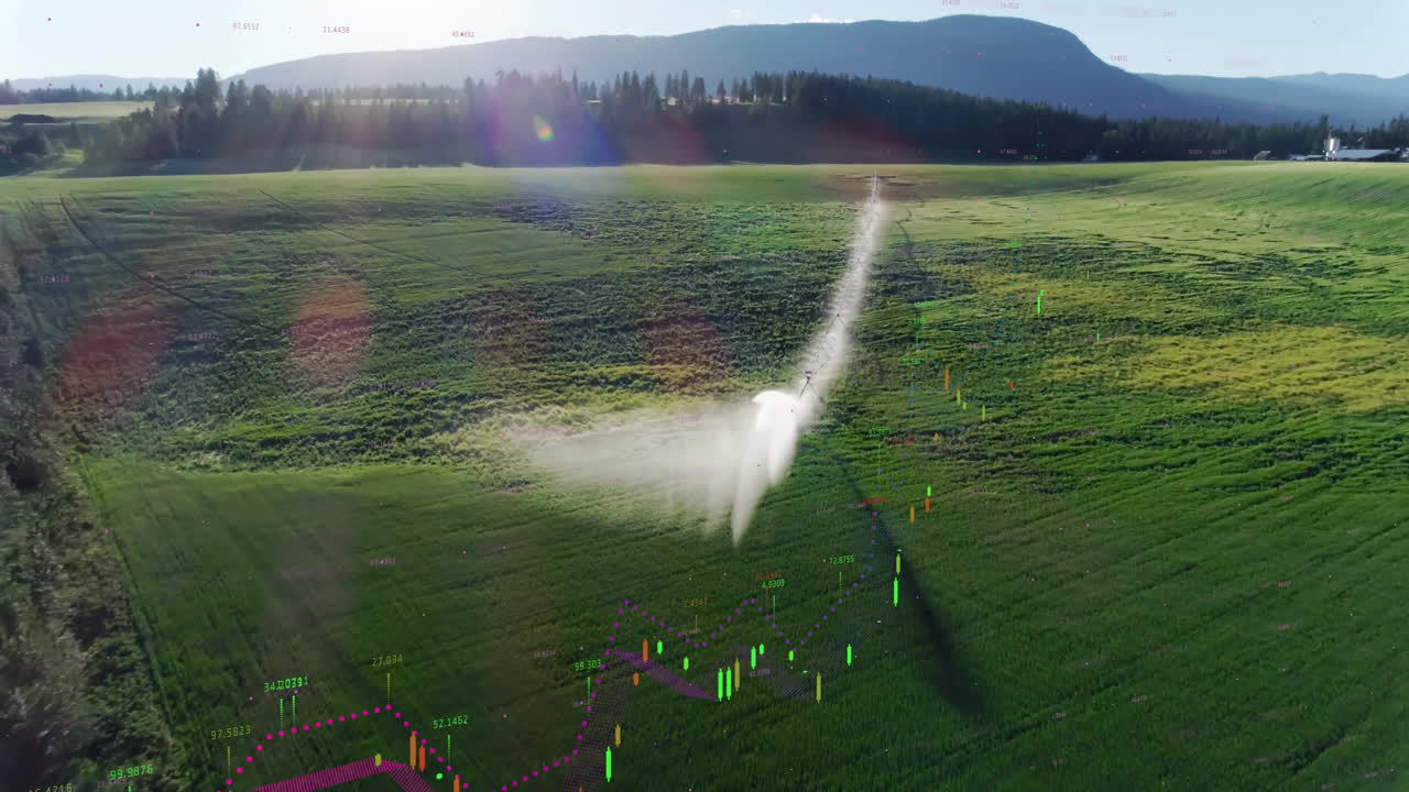 Center-pivot irrigation system spraying mist over crop field, displaying candlestick charts above