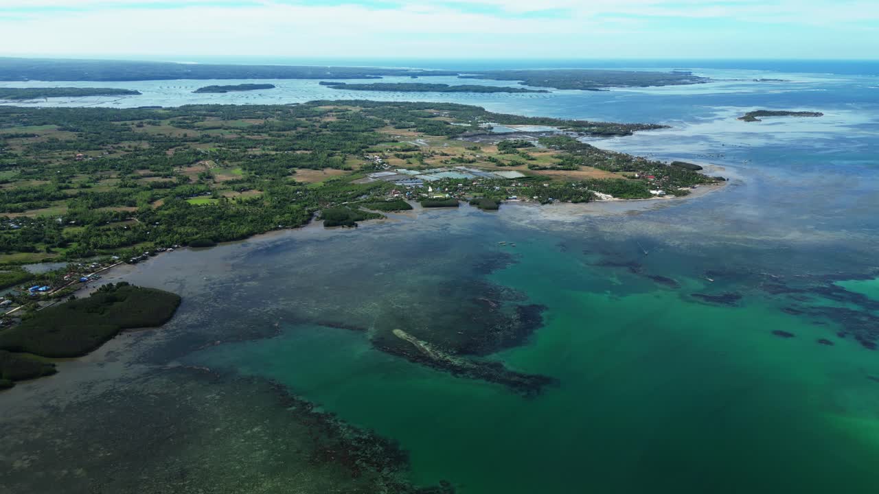 Et bredt luftfoto viser Tondol-øen helt i billedet med palmetræer, lyst hvidt sand og roligt tropisk vand.